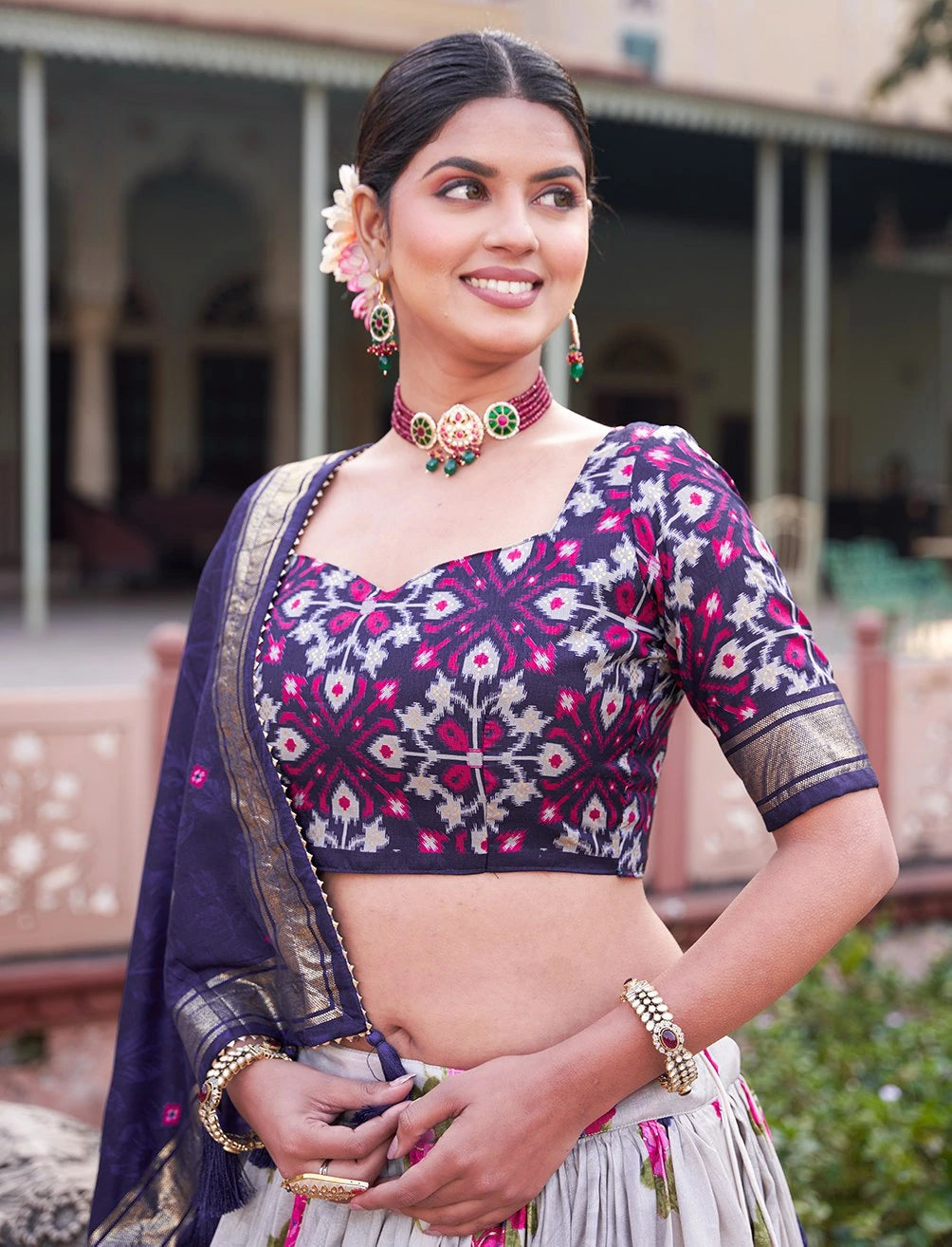 Woman wearing a traditional outfit with a purple and pink blouse in an outdoor setting